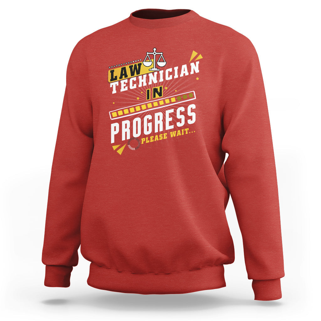 Red crewneck sweatshirt with filmstrip "In Progress" graphic and scales icon