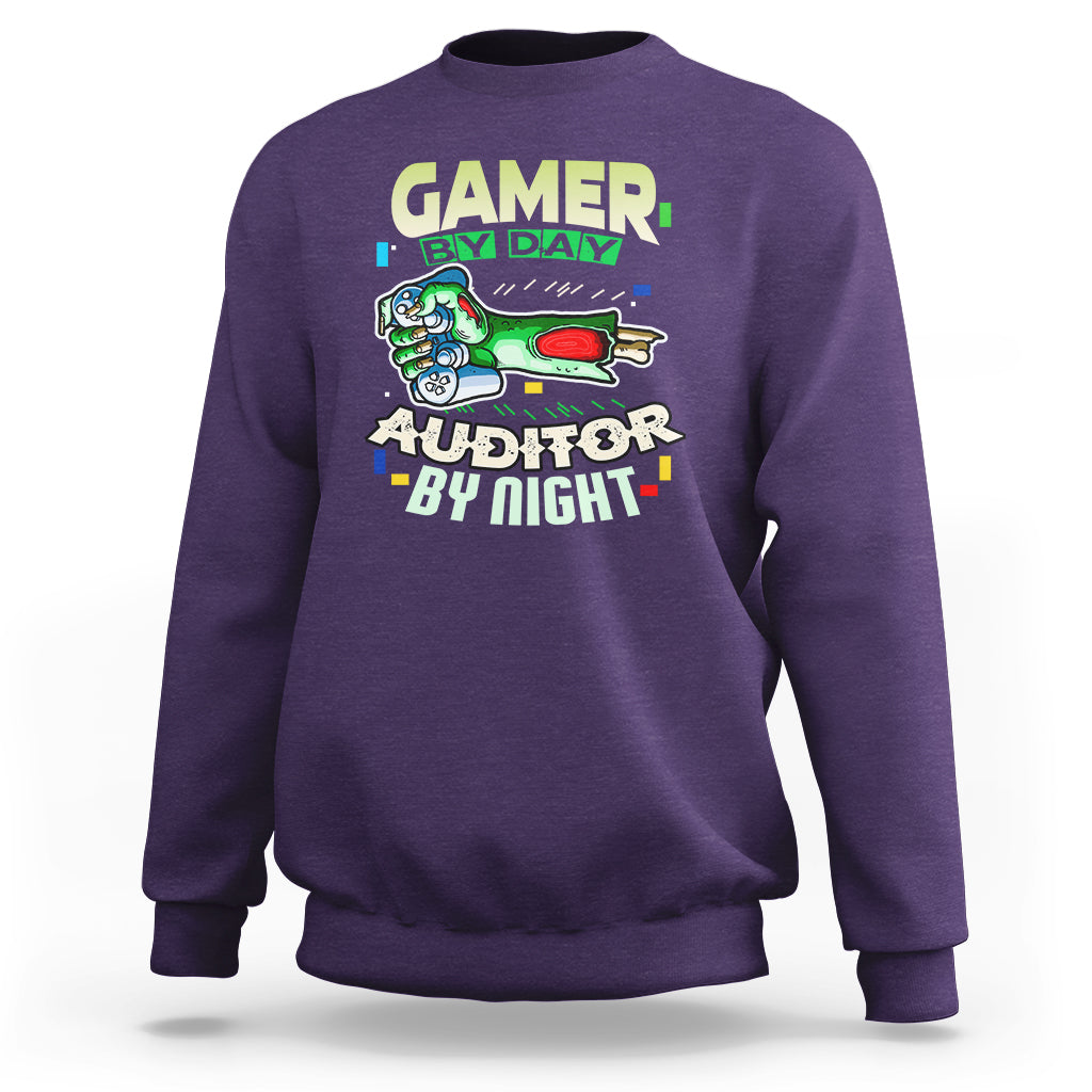 Purple crewneck sweatshirt with “GAMER BY DAY” and “AUDITOR BY NIGHT” chest graphic.