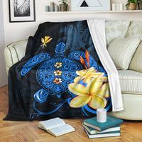 Blue Hawaiian turtle blanket draped on sofa, featuring plumeria and floral mandala