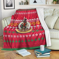 Red Christmas blanket with green tree border and central character emblem, Ugly Xmas style