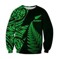 Dark sweatshirt with green fern graphic, RUGBY text, tribal Maori-style print