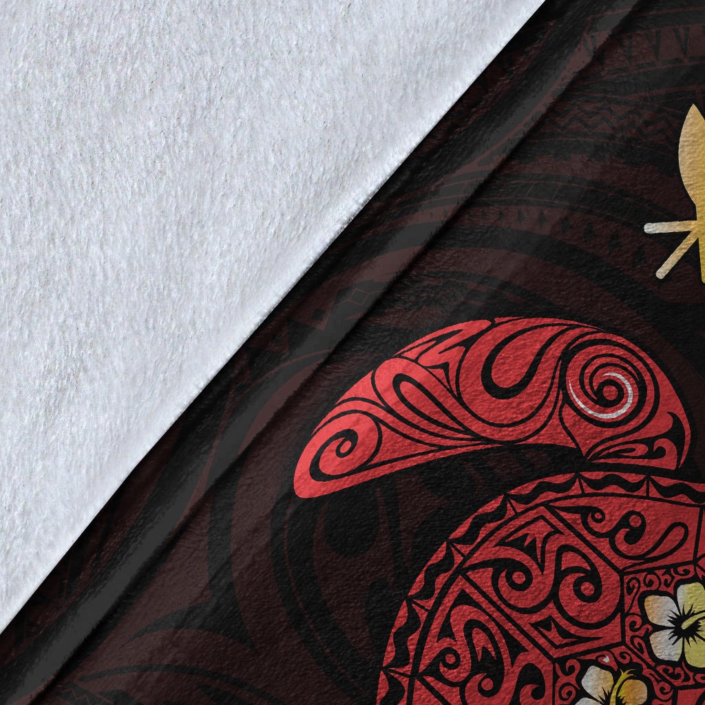 Close-up of Hawaiian blanket pattern: red turtle art and yellow flower accents on dark fabric