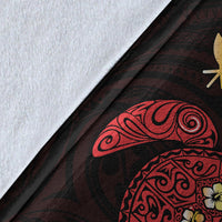 Close-up of Hawaiian blanket pattern: red turtle art and yellow flower accents on dark fabric