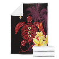 Folded Hawaiian blanket with turtle, palm motifs, and hibiscus flowers in red and yellow