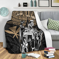 Black blanket with gold tribal border and large white king portrait, on bed