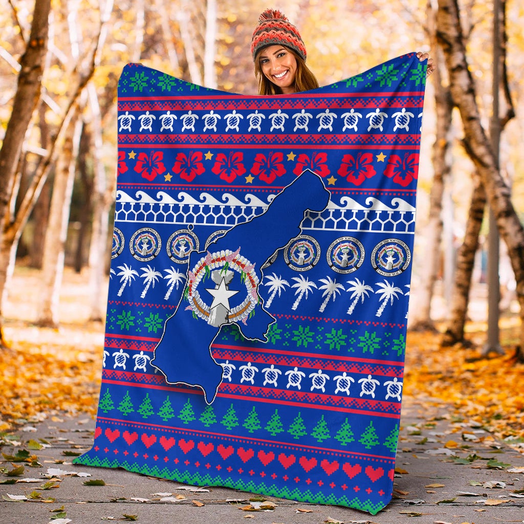 Blue Christmas blanket held up outdoors, showing North Mariana Islands map and festive border