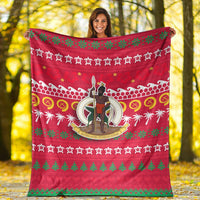 Red ugly Christmas blanket with central character medallion, palm motifs, and green tree strip