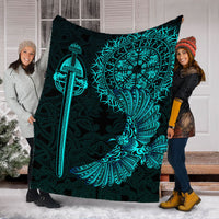 Black blanket with teal Viking raven tattoo design held up, sword and wing graphic
