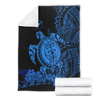 Folded blue sea turtle Polynesian blanket with dark background; includes rolled white towels
