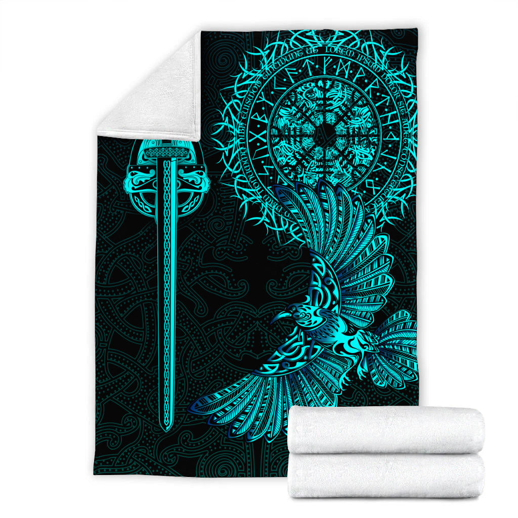 Folded black blanket with teal Viking raven tattoo art; rolled white blanket beside