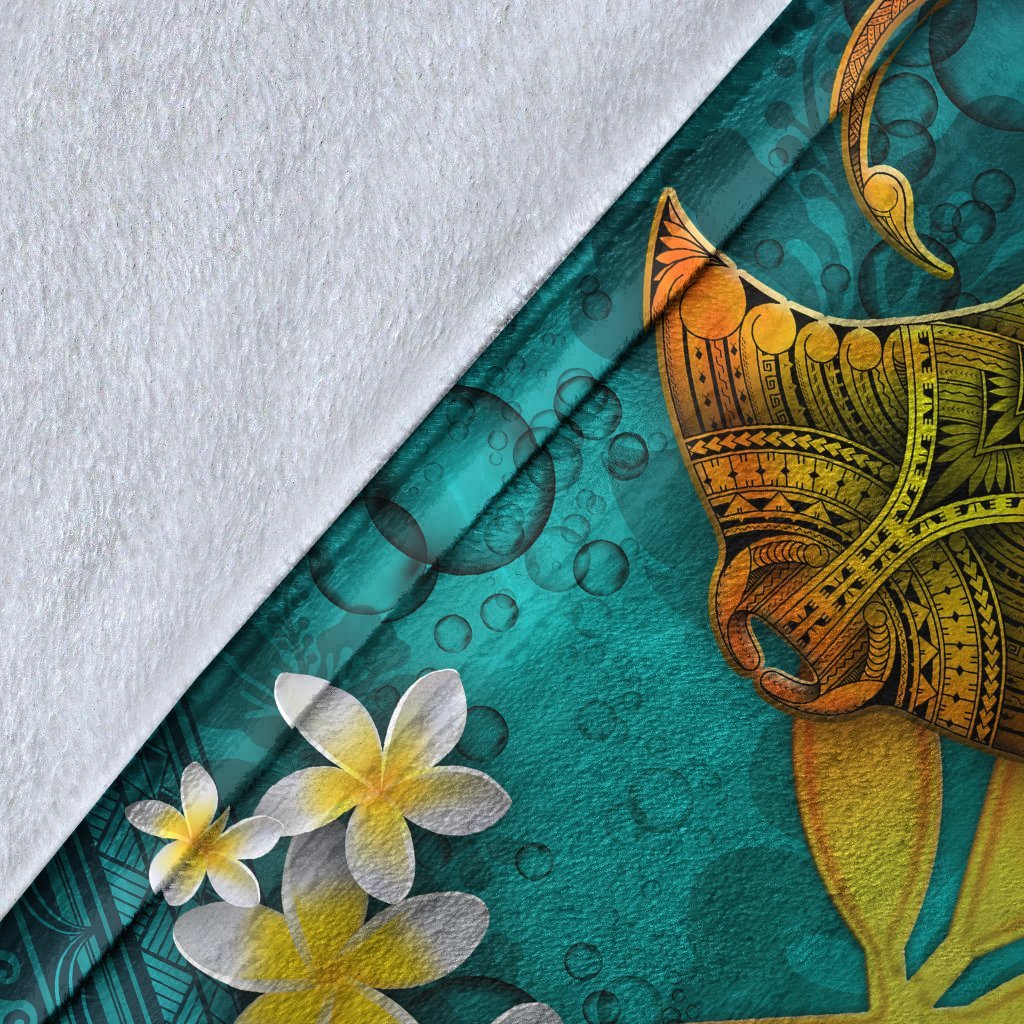 Close-up corner of turquoise manta ray blanket with white plumeria flowers and textured fabric