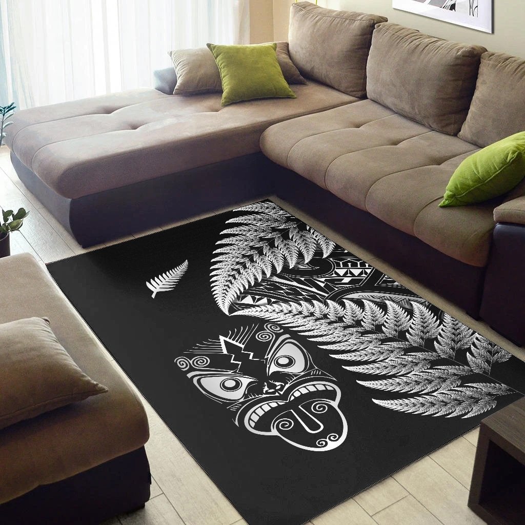 Black rug featuring large white fern fronds and Maori mask motif across center