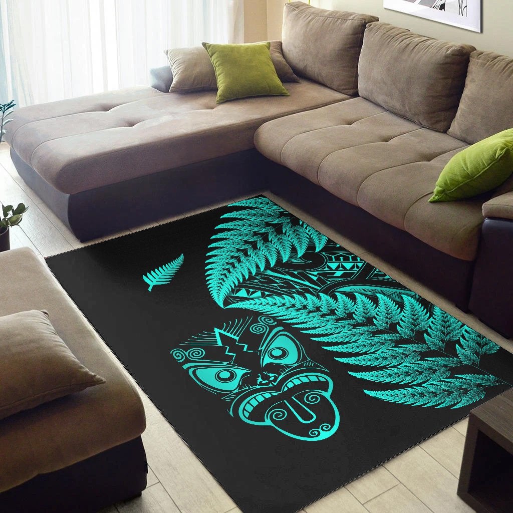 Turquoise fern motif and Maori mask graphic rug laid on floor, dark base