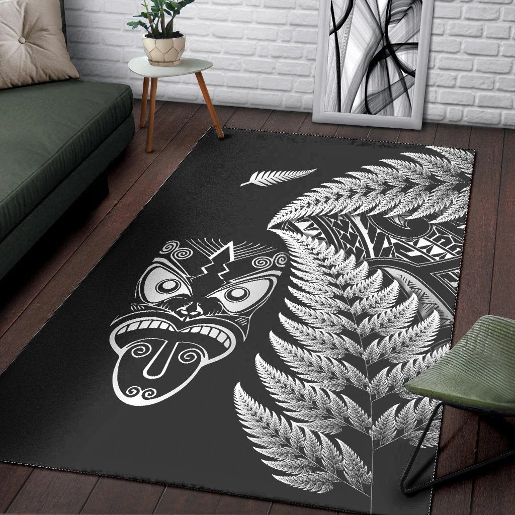 Black rug with white fern fronds and Maori face mask artwork on corner