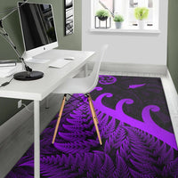 Purple and dark area rug with koru emblem and fern fronds