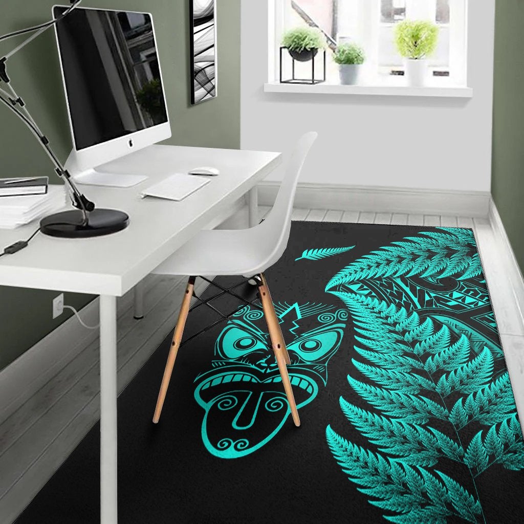 Dark rug featuring turquoise fern leaves and stylized Maori mask symbols