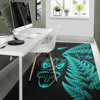 Dark rug featuring turquoise fern leaves and stylized Maori mask symbols