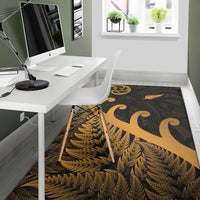 Gold fern frond and koru emblem area rug with dark tribal pattern, rectangular