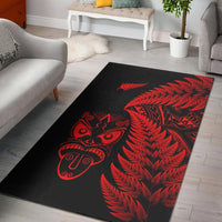 Black area rug with red fern and Māori tiki mask motifs
