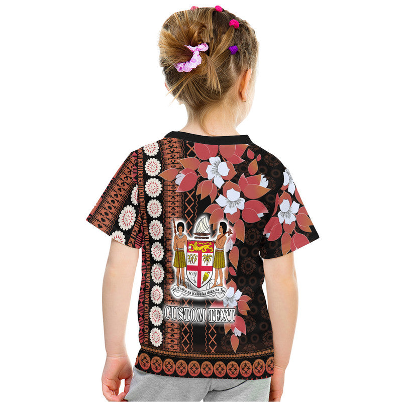 Black tapa-style kids T-shirt, back view with floral print and crest; CUSTOM TEXT