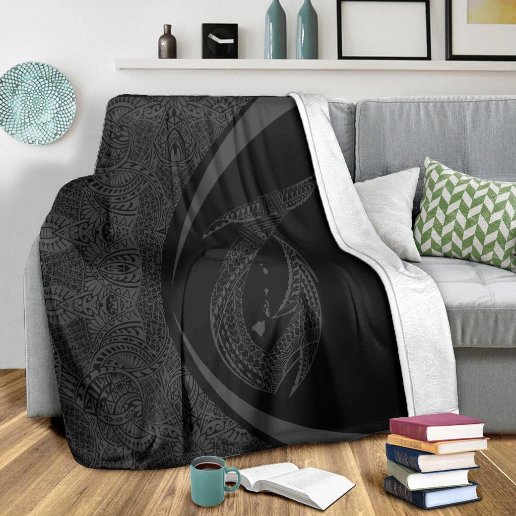 Gray & black Polynesian circle blanket with white border, draped across bed