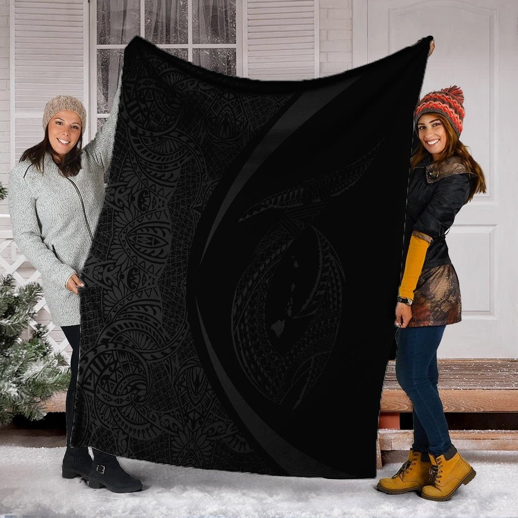 Gray & black Polynesian circle blanket with white border, held up by two people