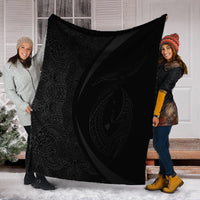 Gray & black Polynesian circle blanket with white border, held up by two people