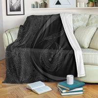 Gray & black Polynesian circle tribal blanket with white border, draped on couch