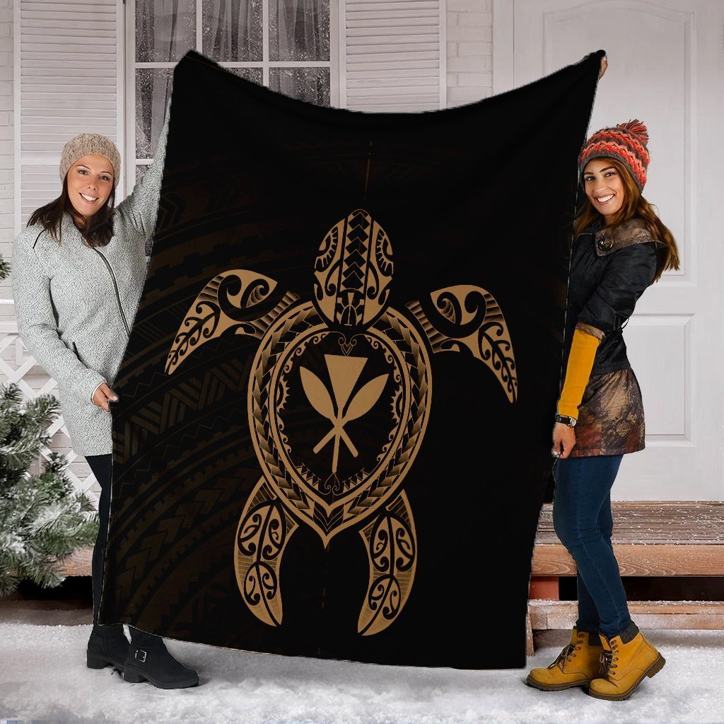 Black and gold Hawaiian turtle blanket held outdoors, showing central turtle emblem