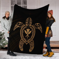 Black and gold Hawaiian turtle blanket held outdoors, showing central turtle emblem