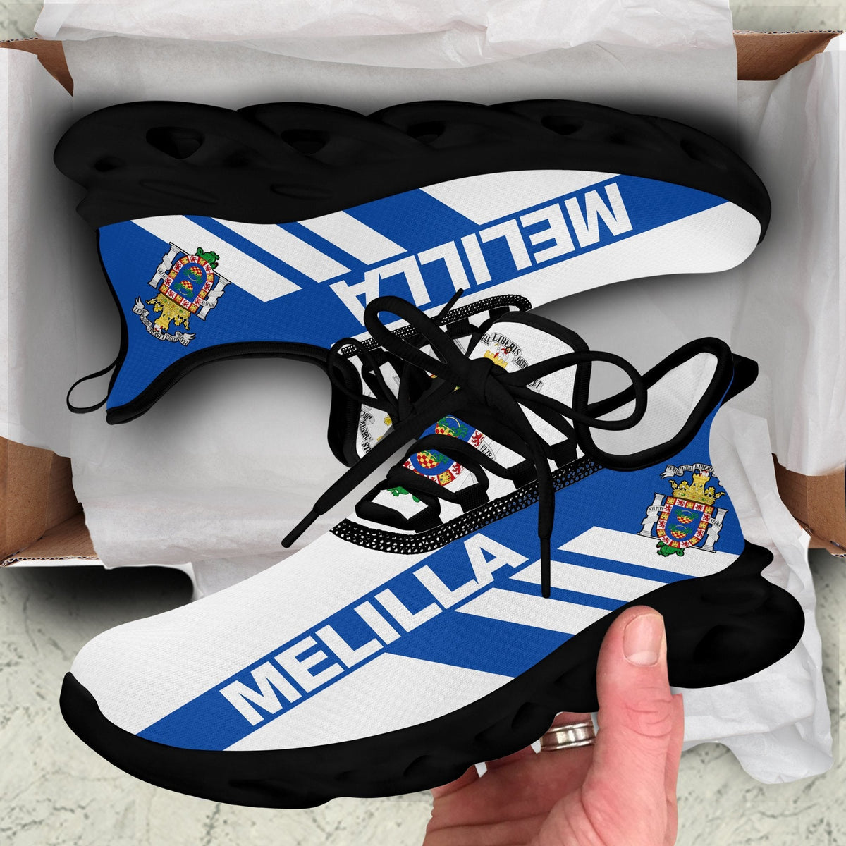 Black clunky sneakers with MELILLA stripe graphic, crest patches, black laces and sole