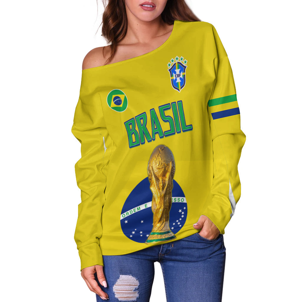 Yellow off-shoulder sweater with BRASIL lettering, crest, trophy graphic, blue-green sleeve stripes.
