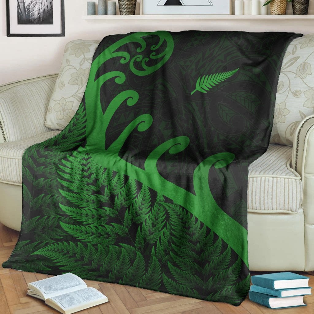 Folded green fern and koru blanket design on dark fabric with bright green patterns