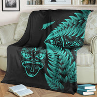 Black blanket with large turquoise fern branch and Maori tribal face graphic, draped