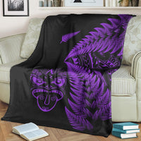 Black fleece blanket draped on couch with purple fern fronds and Maori mask graphic