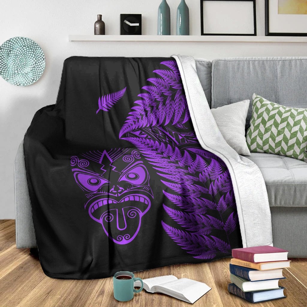 Black blanket with purple Maori face and fern pattern, white reverse lining on edge