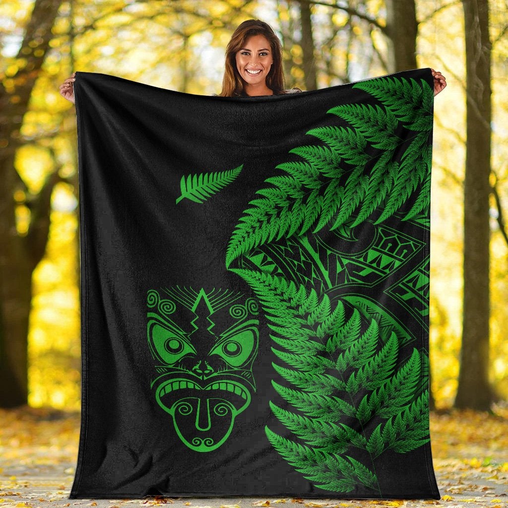 Black blanket outdoors with green fern leaves and Maori mask graphic