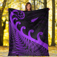 Purple and black blanket held up outdoors with fern pattern and koru swirl designs.