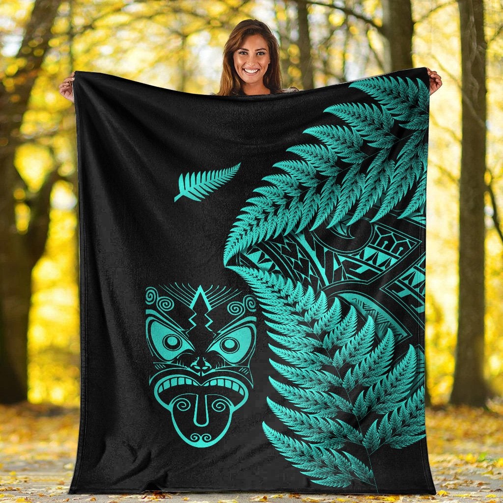 Black blanket held up with turquoise fern fronds and Maori mask artwork, full view