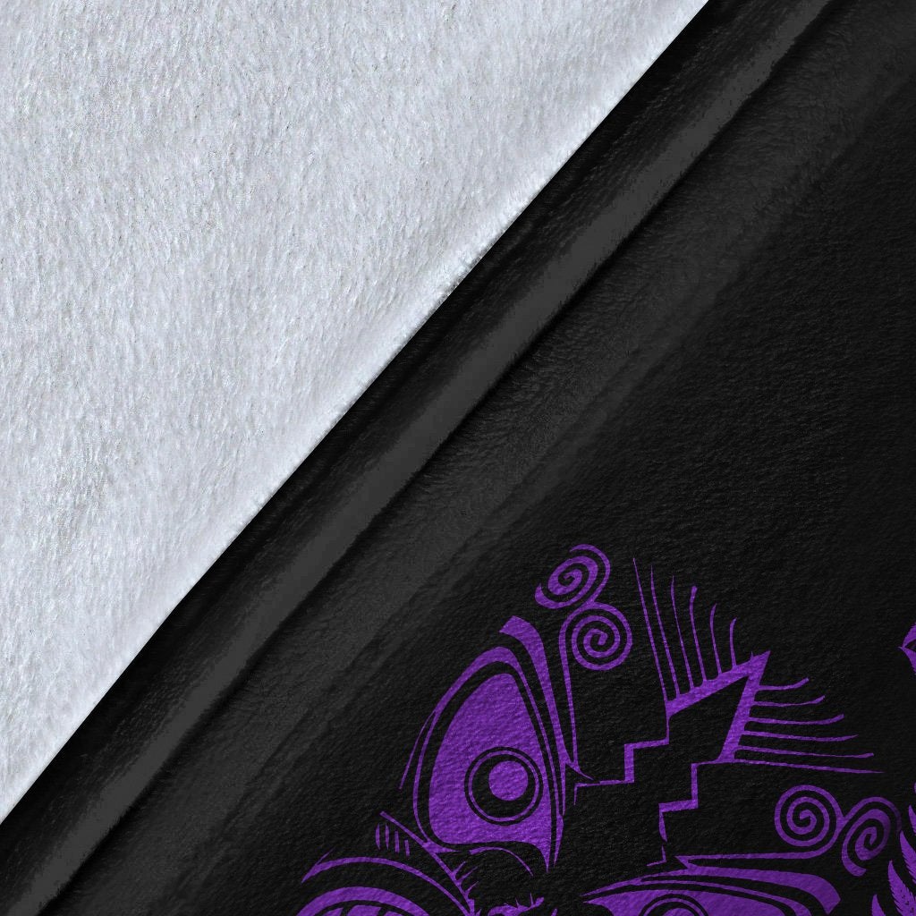 Close-up of black fleece blanket fabric with purple fern-and-mask artwork and white backing