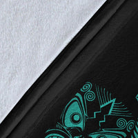Close-up of black blanket fabric with turquoise Maori symbol and fern frond print