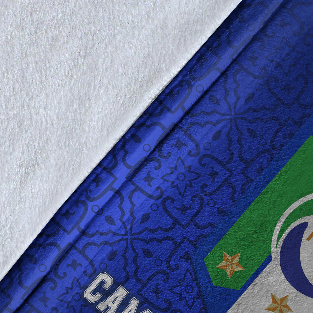 Blue blanket fabric close-up with dark pattern and partial FIGC crest on printed side