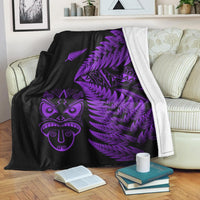 Black fleece blanket with purple Maori face, fern fronds, and white border edge