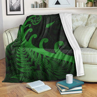 Green and dark green Maori-style koru and fern blanket with black background, draped