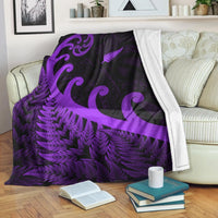 Purple and black fleece blanket with fern and koru patterns, white edge trim visible.
