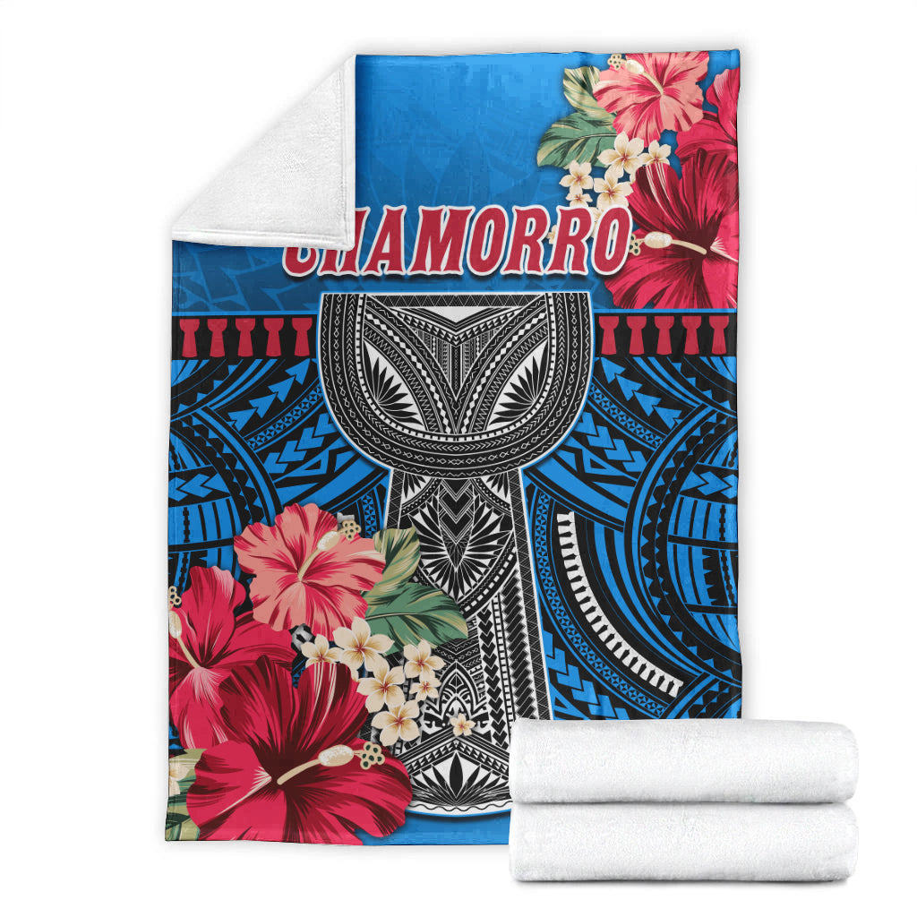 Folded blue CHAMORRO blanket with red flowers and black-and-white tribal oval design
