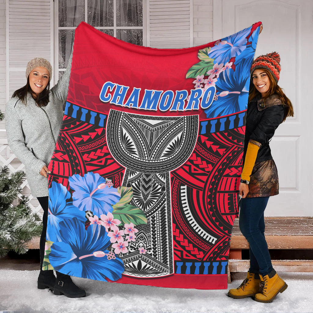 Red Polynesian blanket draped outdoors, Chamorro lettering and blue floral accents