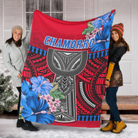 Red Polynesian blanket draped outdoors, Chamorro lettering and blue floral accents