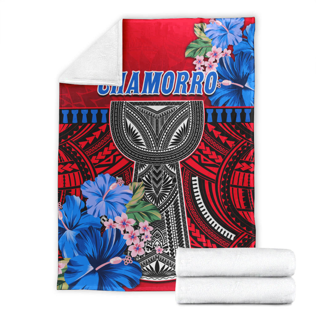 Red Polynesian blanket with Chamorro text, black-and-white mask and blue flowers