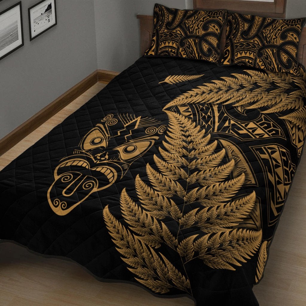Black quilted bedspread with gold fern waves and Maori face symbol; two matching pillows